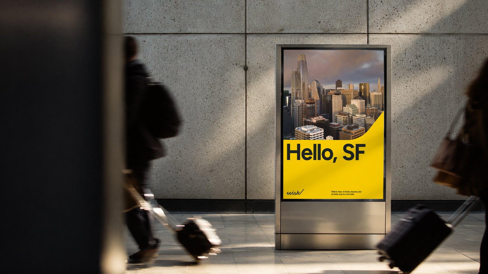 Hello, SF: a yellow Wisk display board in a terminal as travellers pass with luggage