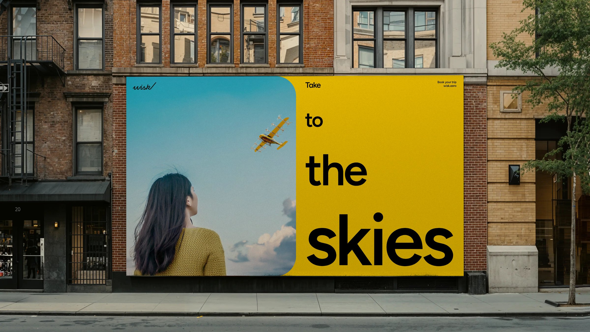 Wisk wall billboard on a city street: Take to the skies, with a woman watching the aircraft fly overhead